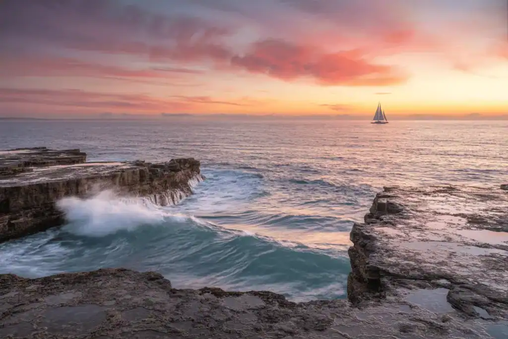 Sailboat gliding into the sunset, symbolizing personal journey, freedom, and alignment guided by life purpose astrology.