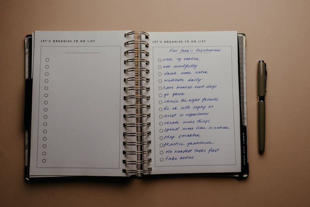 Open planner with New Year's resolutions, spiral binding, and pen on warm-toned background.