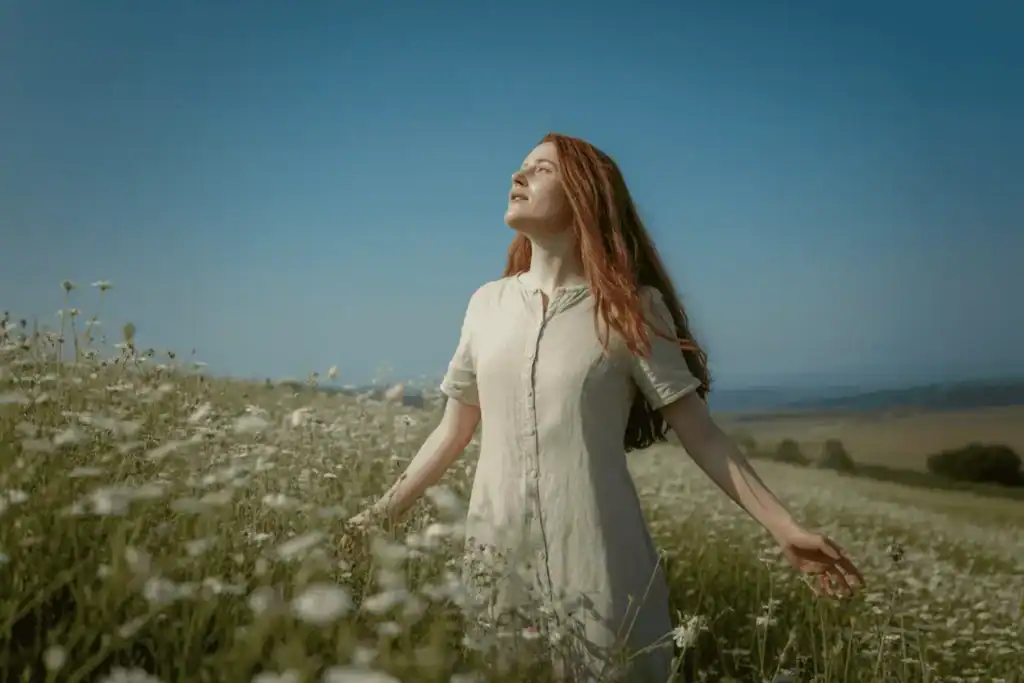 Woman standing in open field under the sky with arms stretched wide, symbolizing clarity and alignment.
