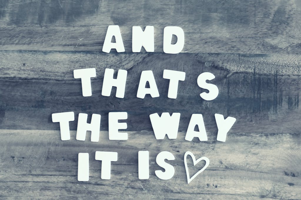 Wooden letters spell 'And that's the way it is' on rustic wood with a heart symbol.